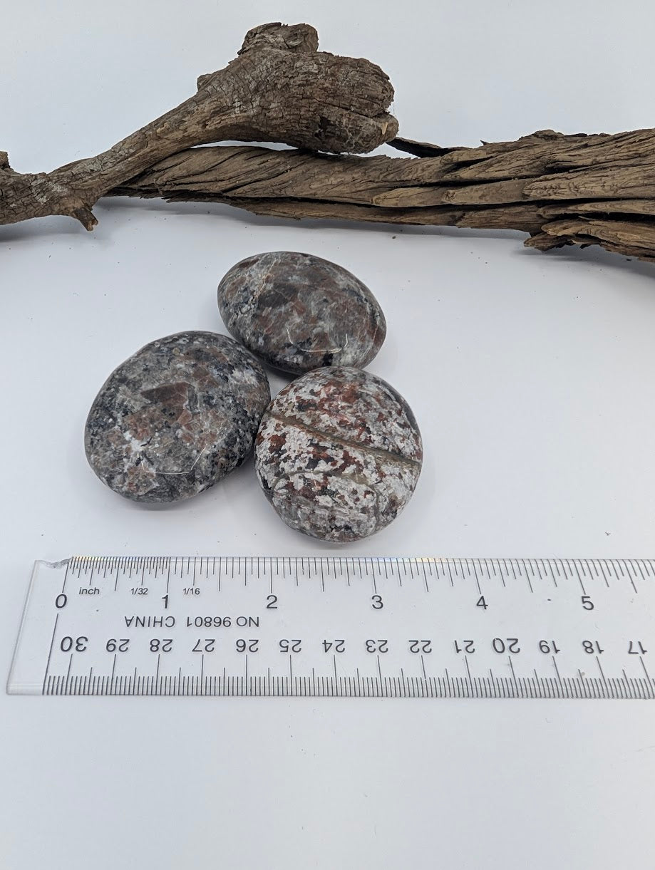 Yooperlite palm stone size reference shown beside ruler (approx. 2.5–3.25 inches)