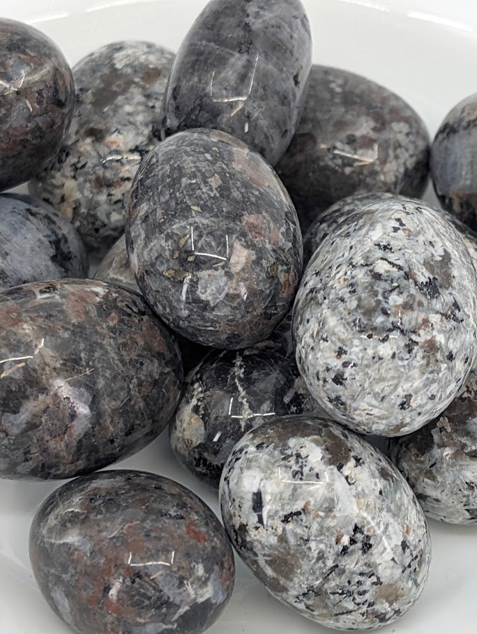 Close-up of Yooperlite tumbled stones highlighting speckled texture and polish