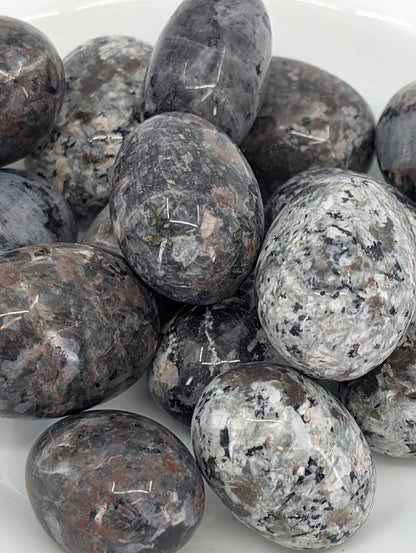 Close-up of Yooperlite tumbled stones highlighting speckled texture and polish